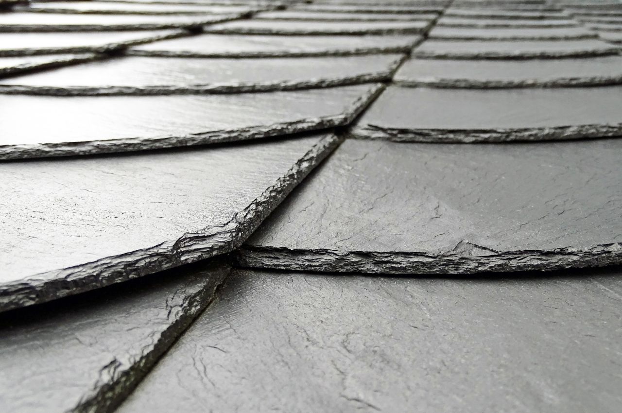 Slate Roofing Among the types of roofs, slate roofing offers unmatched durability and beauty. Slate shingles are a natural stone roofing material. Thus, many people love their unique beauty. One of the things about slate shingles is that they are heavy. So, you need to have a strong roofing structure to withstand the load. Also, these shingles have outstanding water and damage resistance properties. Like natural stone, they come in limited colors like green, black, gray, or red. But here is the thing, "every slate shingle offers unique beauty." There are not two slate shingles alike. According to HomeAdvisor, a 17-square residential roof of a high-end slate costs $20,000. A slate roof is twice as expensive compared to a shingle roof that costs between $6,500-$9,000. Slate roofing is worth the cost since it will last from 60 to 150 years. When you own a slate shingle roof, you'll need to rely on a slate shingle professional for repairs. Since slate shingles are a high-end roof, DIYers will face serious injury risks when repairing slate roofs. Also, instead of fixing it, they can ruin the roof structure. Tile Roofs (Concrete or Clay) Concrete or clay are two popular choices for colonial-style homes. The concrete tile roof is heftier than the clay roof. Concrete tile roofs are heavy and powerful. If you are looking to install them, you need to hire a structural engineer or framing contractor. This professional will add extra framing if necessary, to make sure your house can bear the weight for years to come. Concrete roof tiles come in a wide variety of styles and colors. Some architectural styles include Venetian, Spanish, and New England Colonial. The tile can be flat or round. It all depends on your tastes and desired house facade. So, if you choose concrete tiles, you'll have an easier time matching your roof with your house facade's colors. Both concrete and clay tile outlast other roofing materials. Most manufacturers offer warranties from 50 years to the life of the structure. Wood Shingles Wood shingles offer a unique and classic look to your home. But since wood burns, they are not always allowed by building codes due to fire hazards. Thus, you have to make sure the local building codes approve your wood shingles. One of the most common types of wood shingles is cedar shingles. They offer a smooth and uniform look for your roof surface. If you want to give your house a more rustic look, you can choose cedar shakes. Cedar shakes have a rugged appearance. And each piece looks different from the rest. So, you can get both a uniform look or a rustic look as you wish. When it comes to durability, wood shingles have a lifespan of 20 to 25 years.